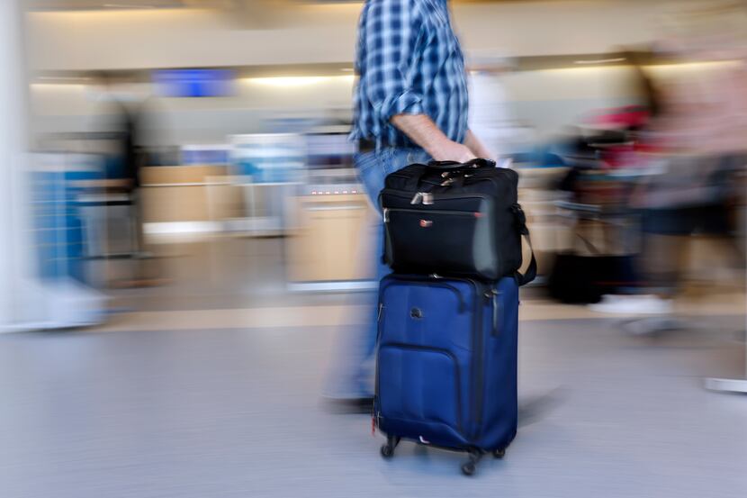 An American Airlines passengers rolls his luggage to check-in in Terminal A at Dallas-Fort...