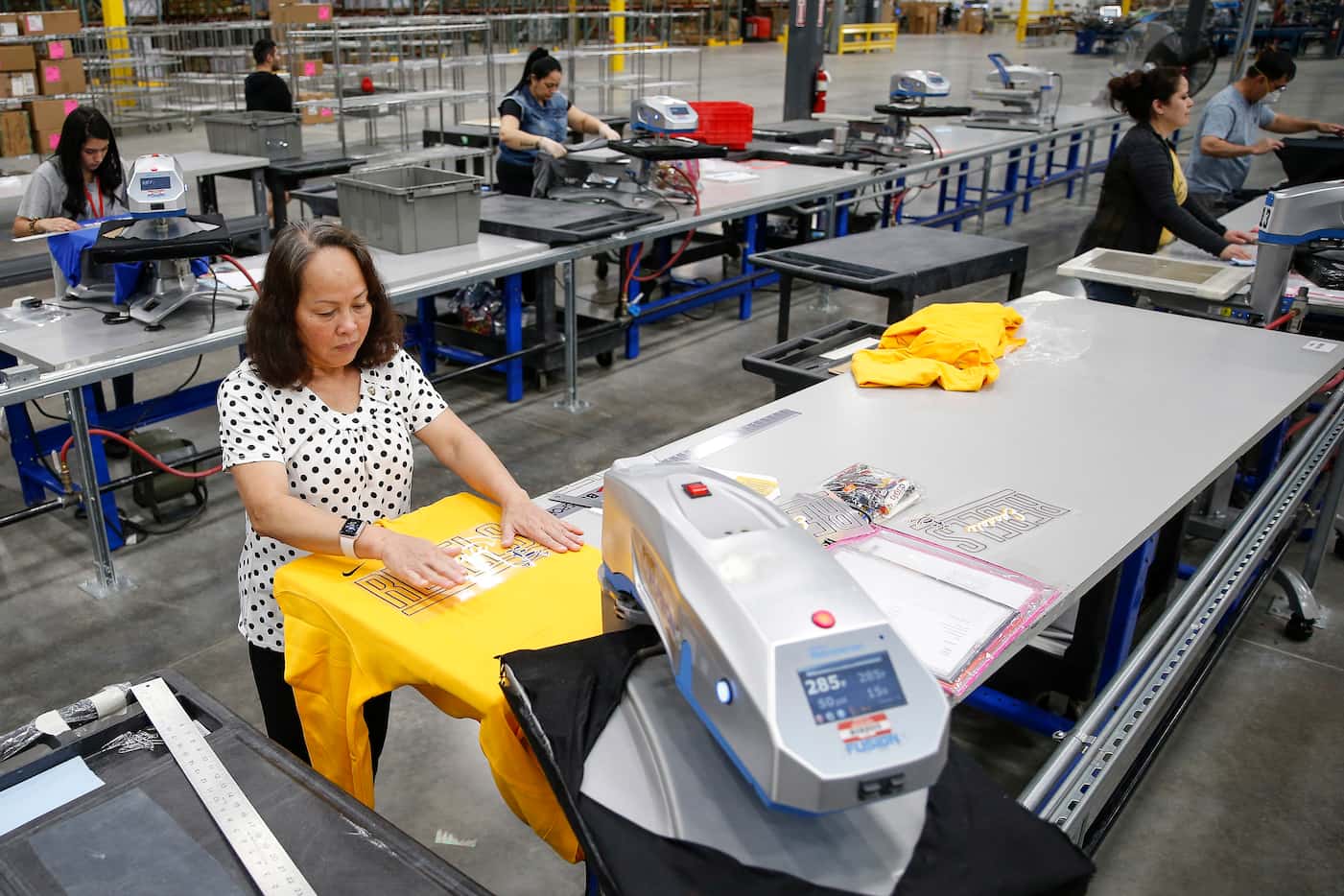 Workers fulfill custom design apparel orders at BSN Sports on May 7 in Grand Prairie. The...