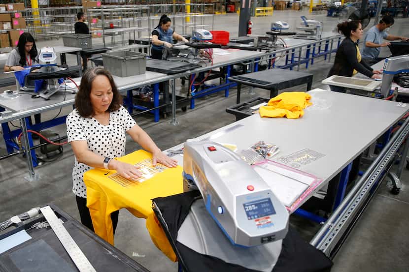 Workers fulfill custom design apparel orders at BSN Sports on May 7 in Grand Prairie.