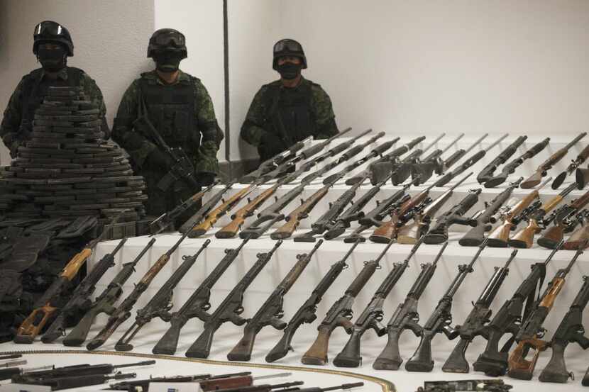 Soldiers stand guard during a media presentation of a weapons cache that includes 154 rifles...