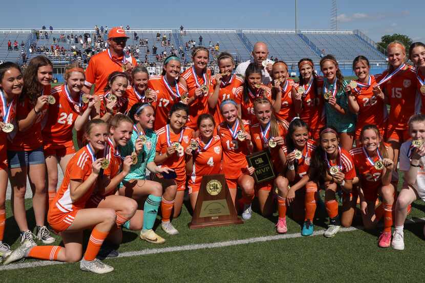 Celina players and coaches pose with the state championship trophy following their 8-1...
