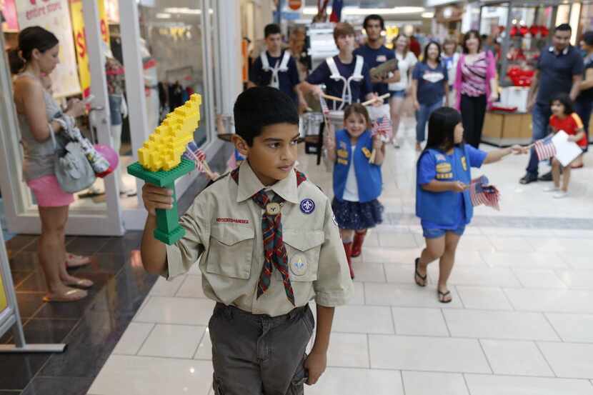 Ryan Alonzo, 10, of Carrollton holds a torch made of LEGO pieces marches in a parade with...