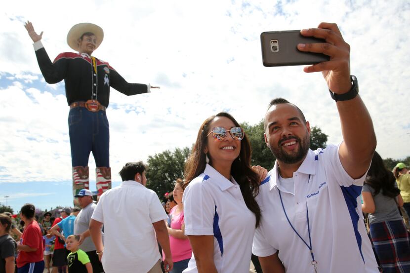 Dennis Jansen and Cassandra Jaramillo take a selfie with Big Tex at the State Fair of Texas.