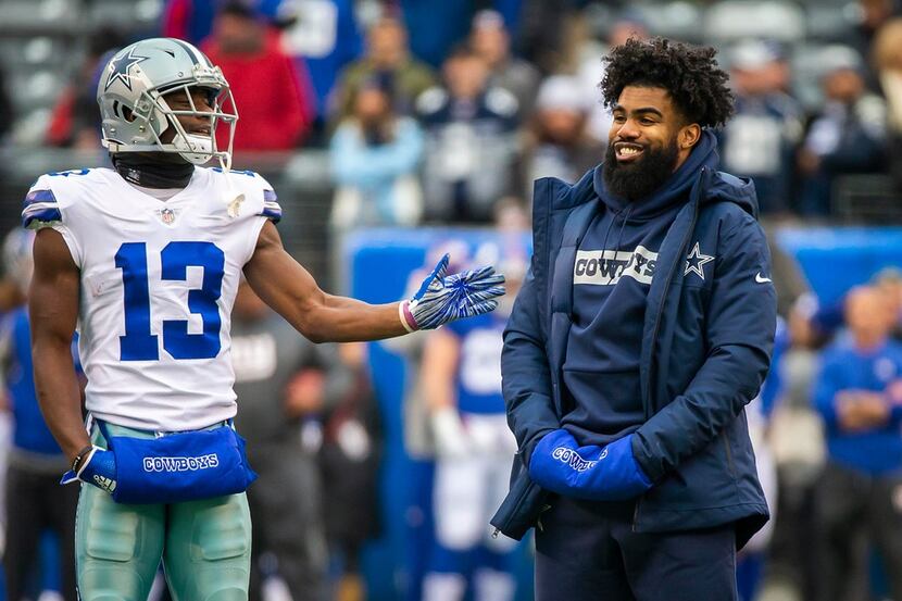 Dallas Cowboys running back Ezekiel Elliott, who was not in uniform for the game, laughs...