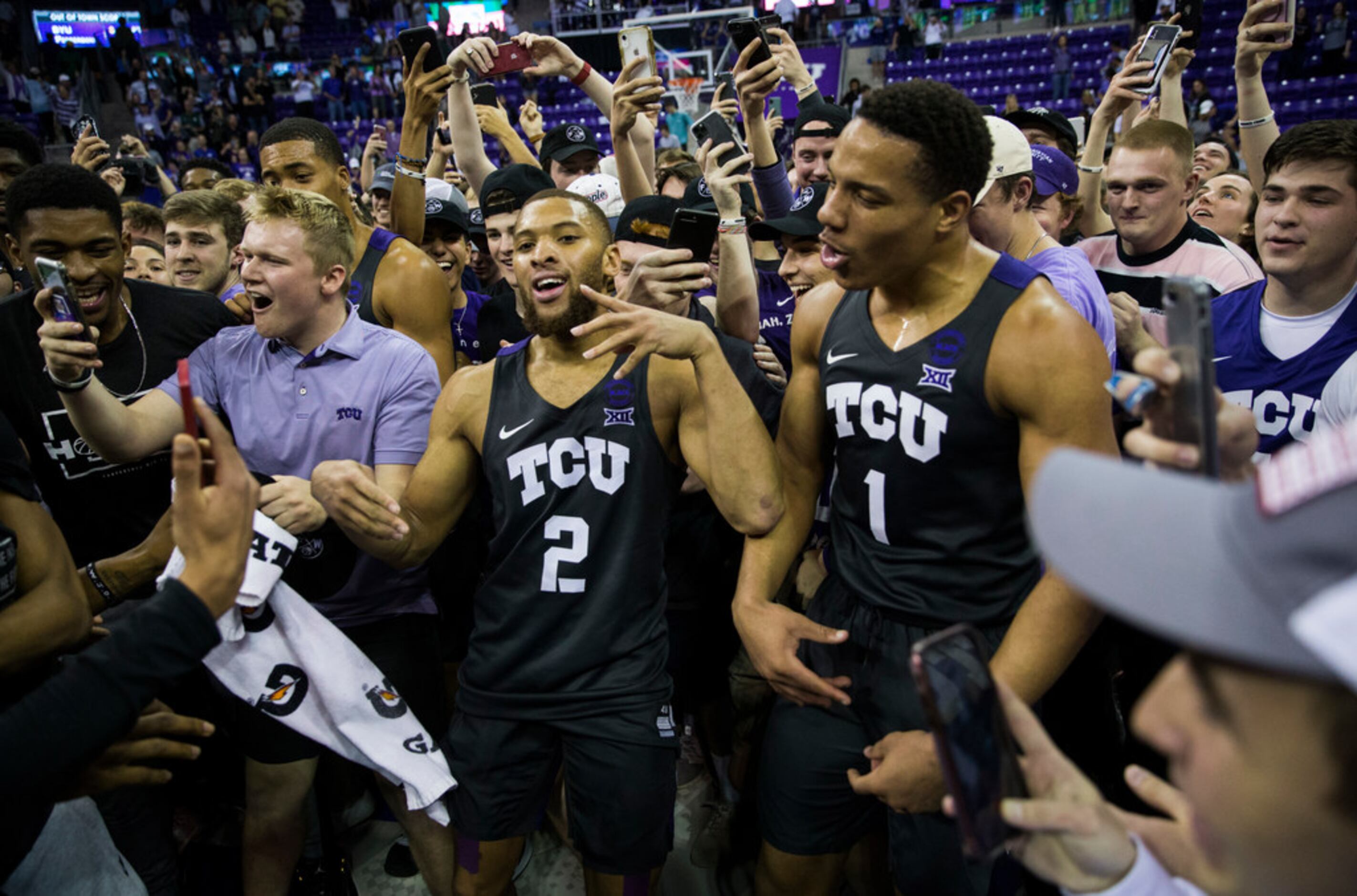 TCU Horned Frogs guard Edric Dennis (2) and guard Desmond Bane (1) celebrate after fans rush...