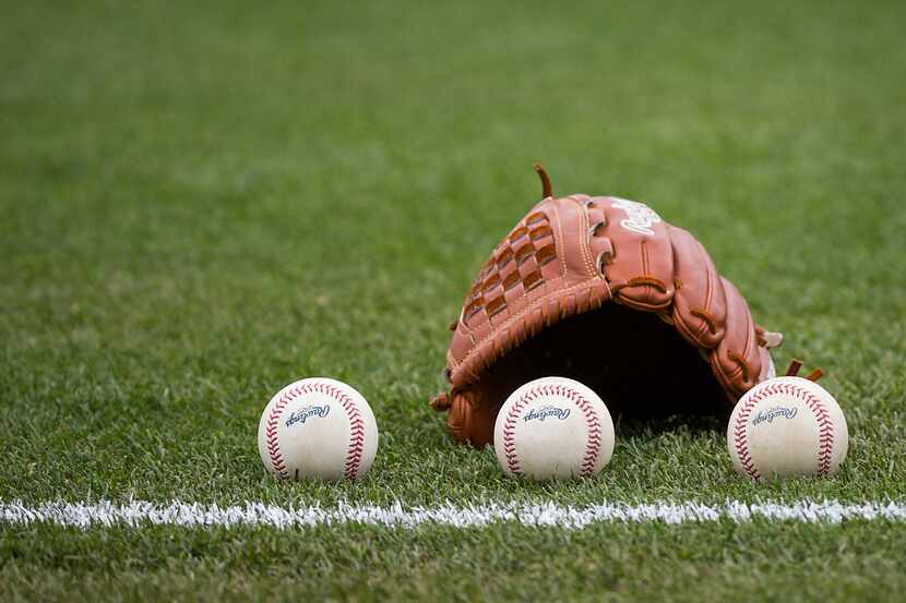 Balls rest next to the glove before a Texas Rangers spring training game against the Seattle...