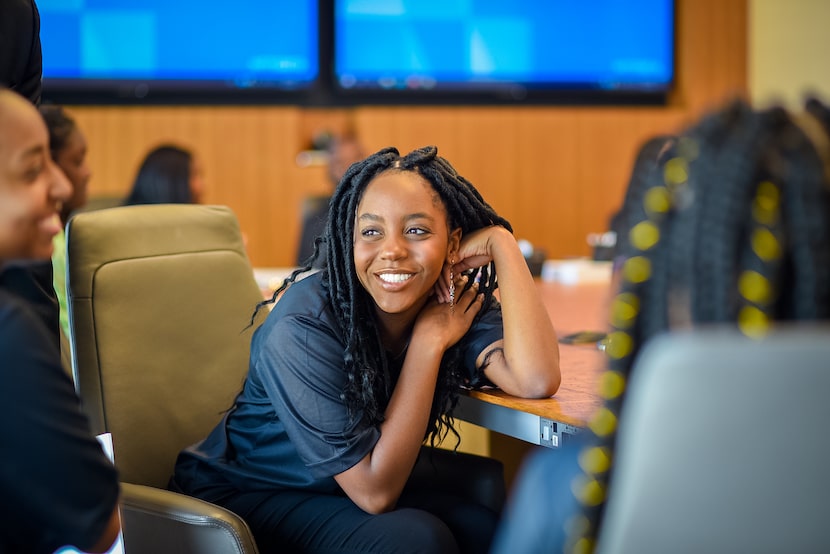 Paul Quinn graduate Evelyna Rosario sits at a desk while smiling at her Corporate Work...