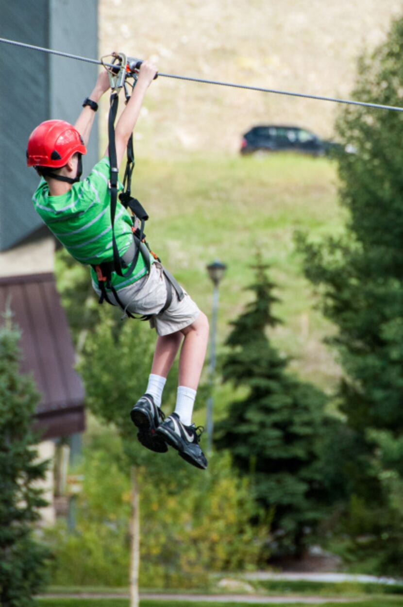 A young rider zips over West Lake at the Copper Mountain Ski Resort.  The 300-foot cable is...