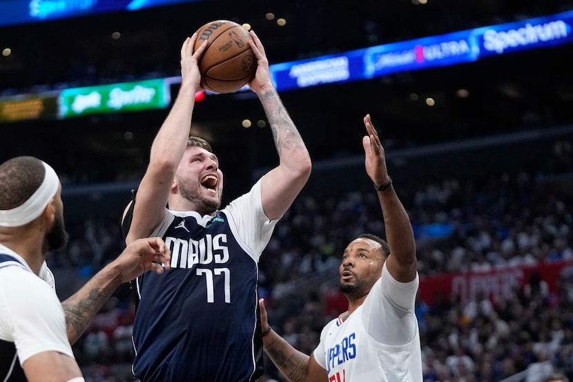 Dallas Mavericks guard Luka Doncic, center, shoots as Los Angeles Clippers guard Norman...