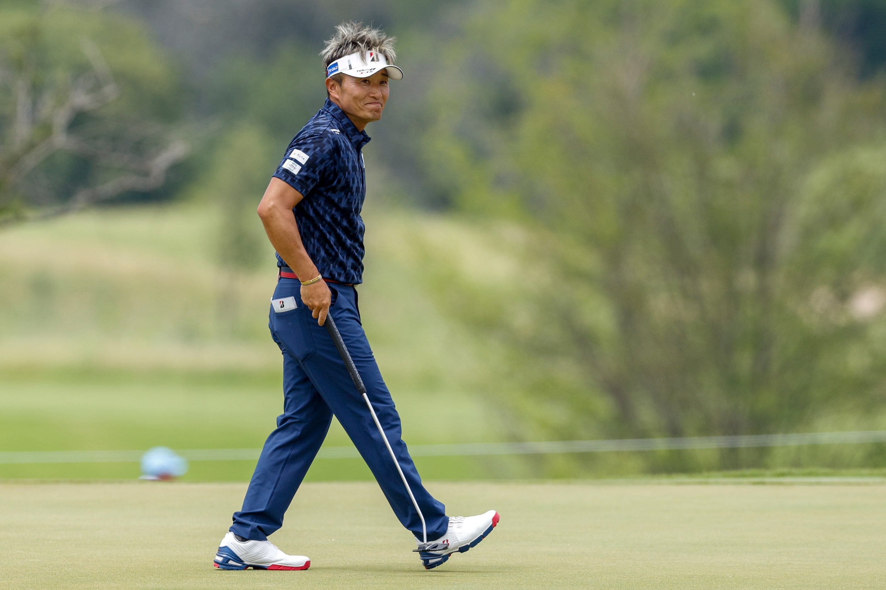 Katsumasa Miyamoto of Japan smiles as he readies to putt on the 18th green during the first...