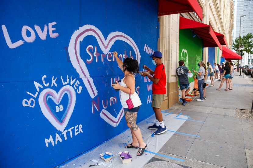 Bryana Otero, left, and Brannon Ridgley, both of Dallas, paint a mural on boarded-up windows...