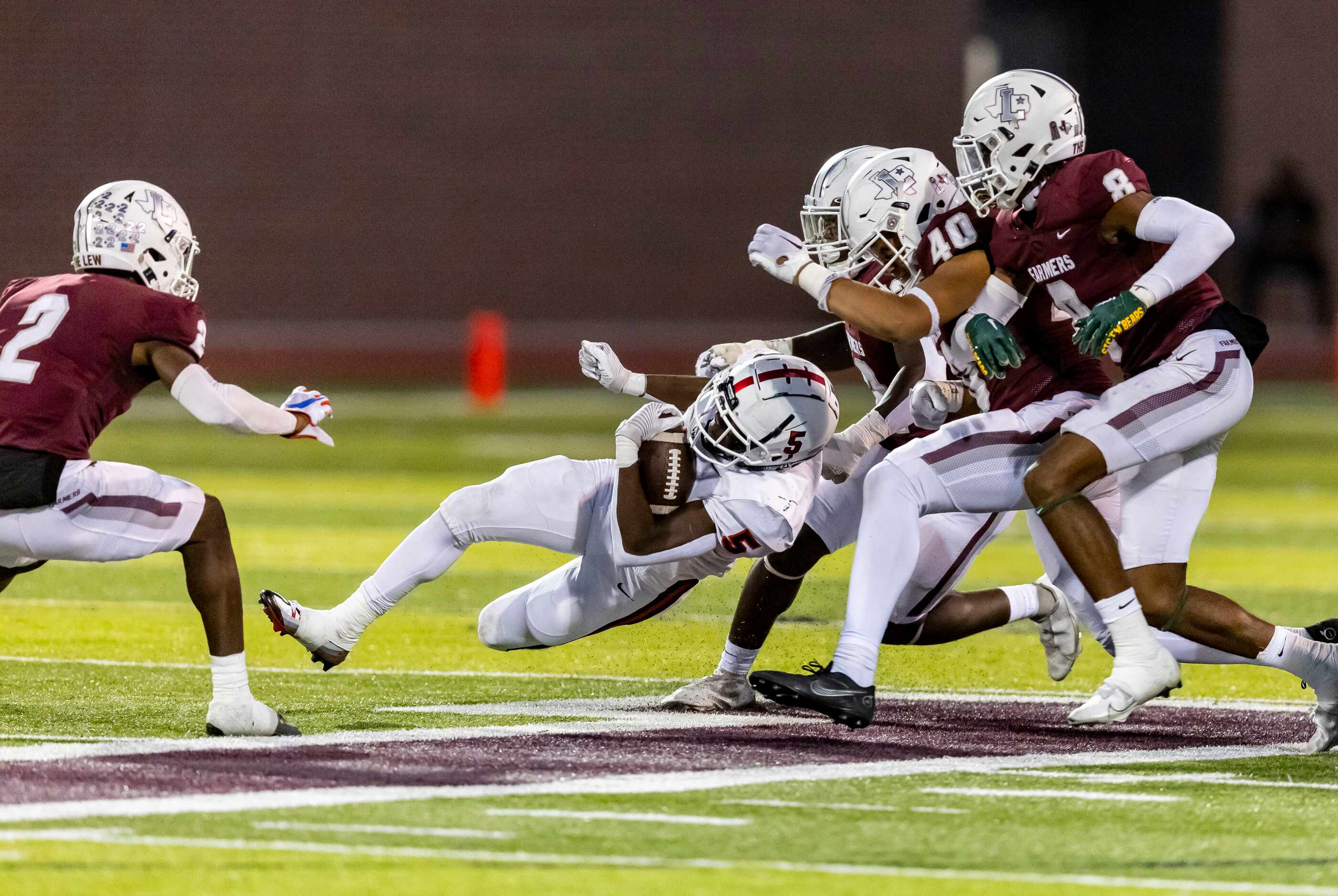 Coppell senior running back Malkam Wallace (5) is tackled by the Lewisville defense during...