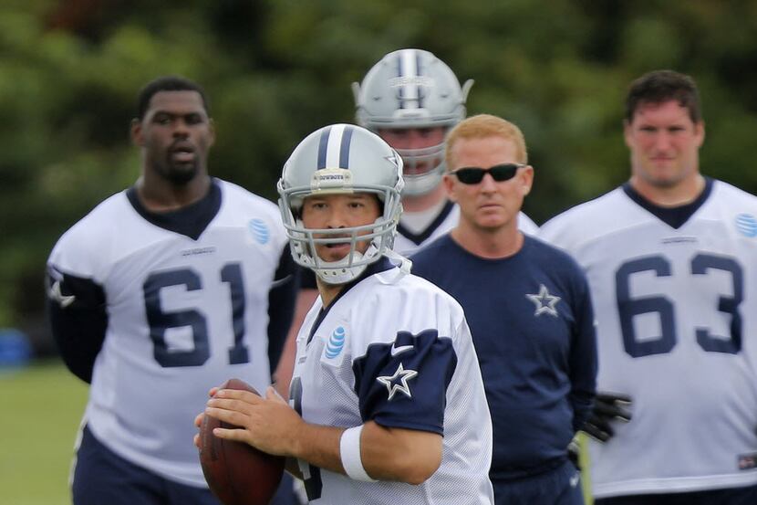 Dallas Cowboys rquarterback Tony Romo passes as head coach Jason Garrett looks on at an...