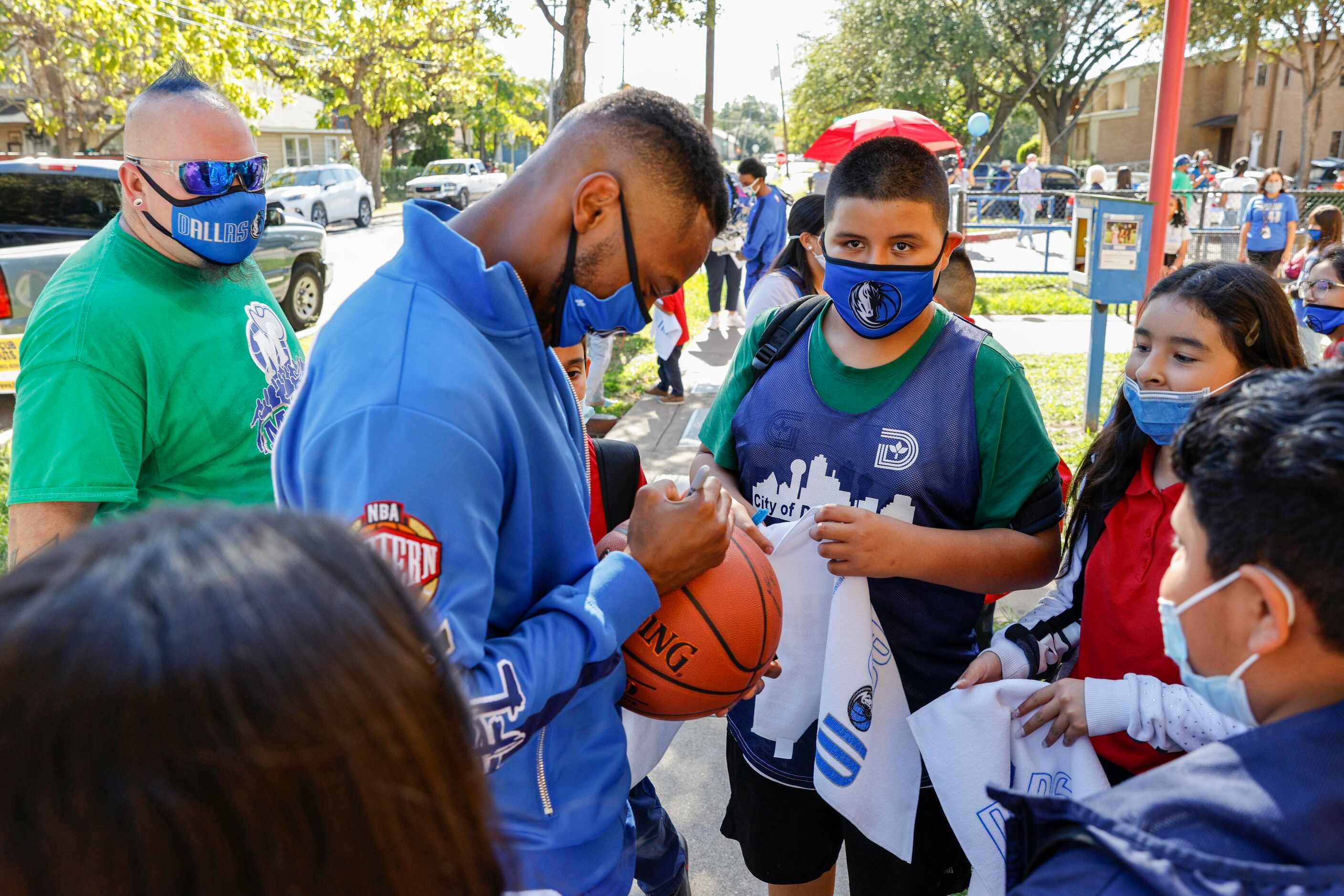 Dallas Maverickss D-Town Dance Crew member Dante harpe autographs a basketball for a student...