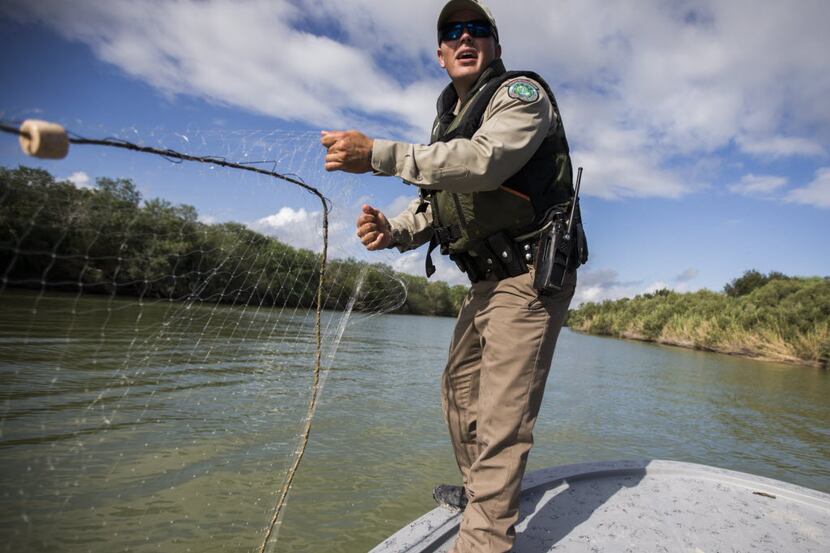 Texas Parks and Wildlife Game Warden Colby Hensz checks a gill net in the Rio Grande River...