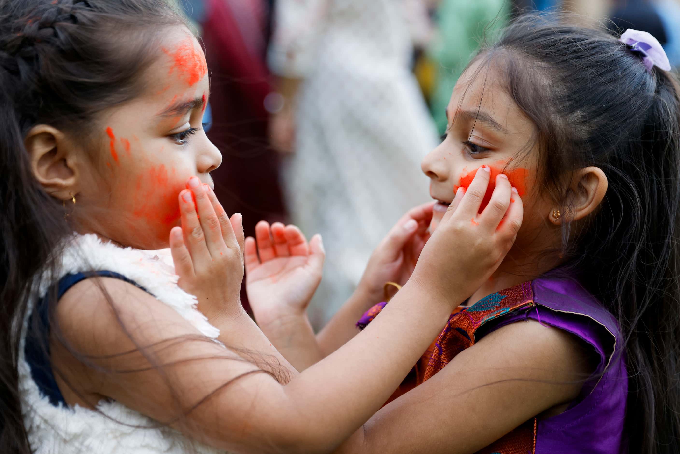 Amayra Patel, 4, (left), applies color on her cousin Trisha Patel, 4,  during Holika Dahan,...