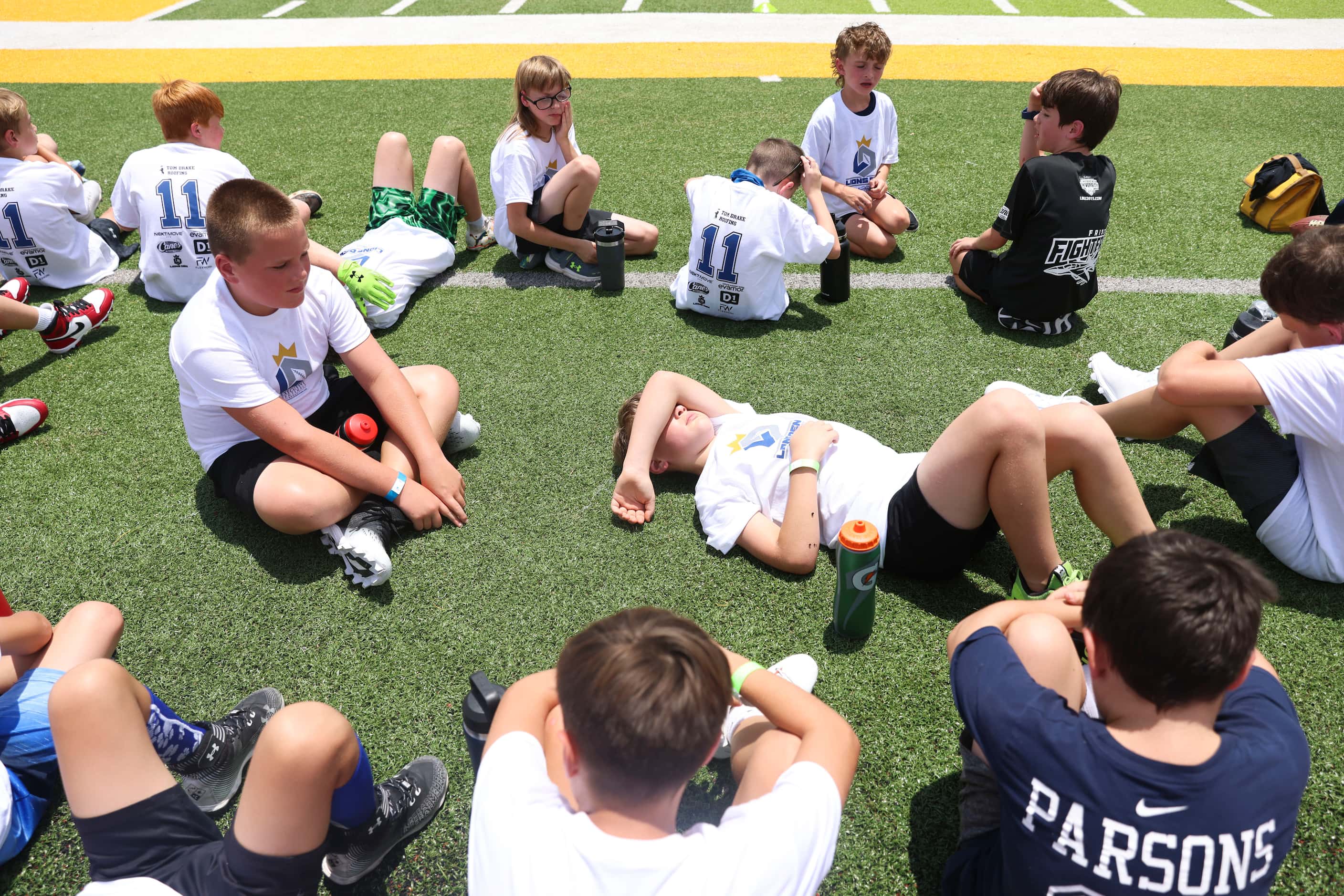 Young football players gather ahead of practice and interacting with Dallas Cowboys...