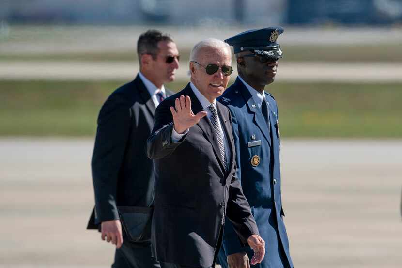 President Joe Biden waves as he walks with Col. Carlos Alford, Commander of the 89th Airlift...