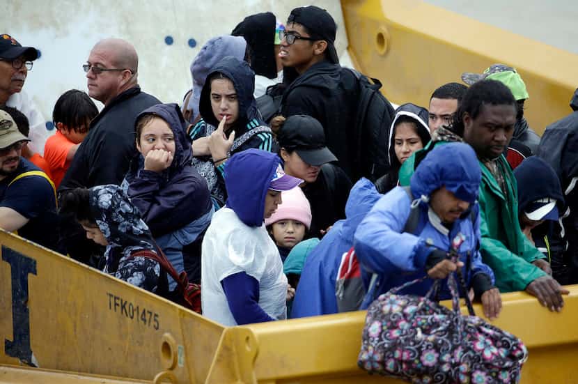 Flood victims wait to unload from the back of a heavy duty truck after being evacuated from...