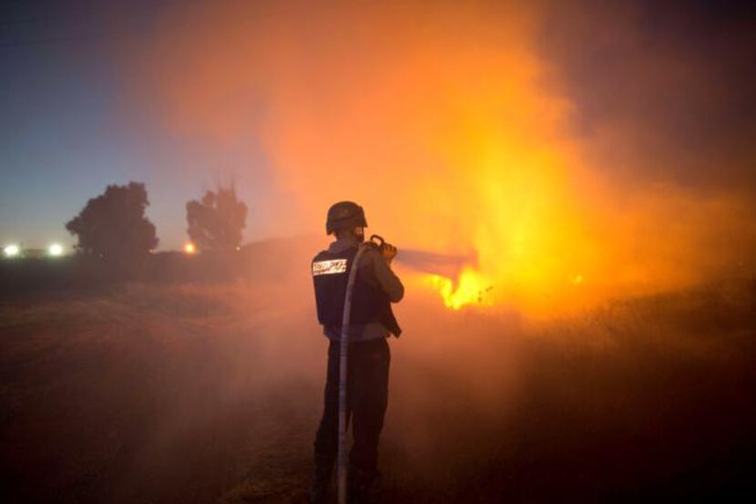 
An Israeli firefighter extinguishes fire after rockets fired by Palestinian militants from...