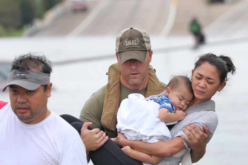 Houston SWAT Officer Daryl Hudeck carries Catherine Pham and her 13-month-old son, Aidan, to...