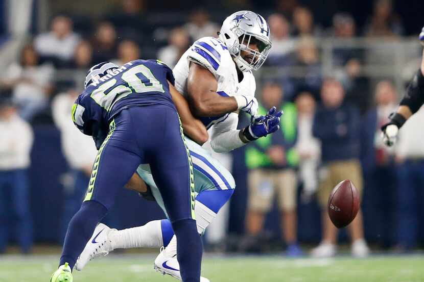 Dallas Cowboys running back Ezekiel Elliott (21) drops the ball as he is hit by Seattle...