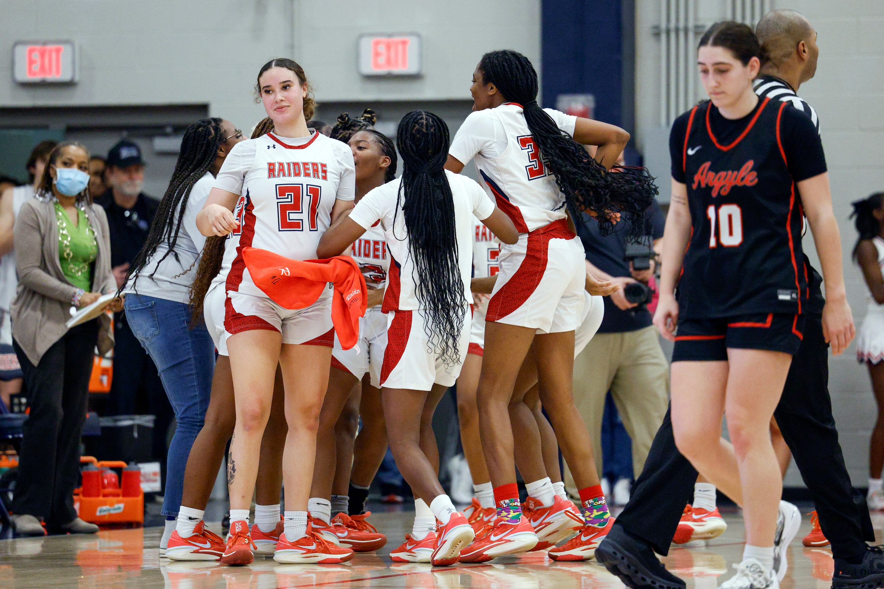 Denton Ryan players celebrate an overtime win in a District 7-5A basketball game against...