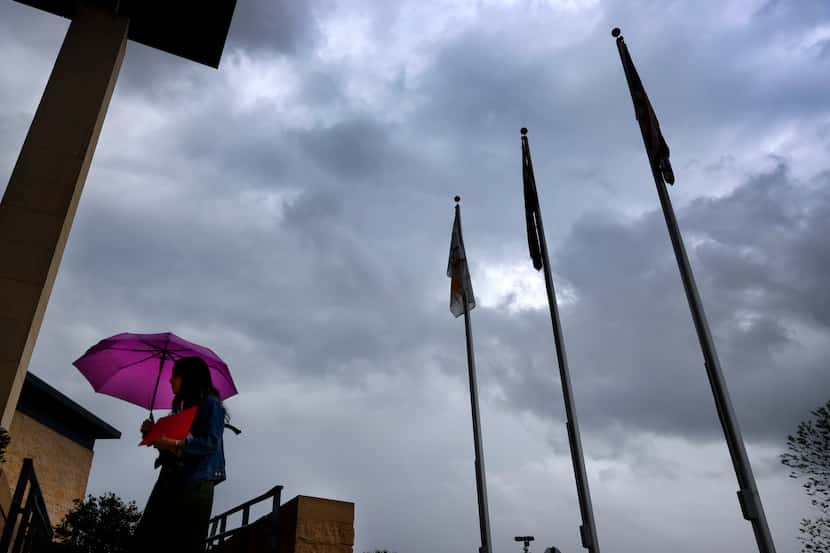 Kelly Camarillo navigates the rain falling as she arrives at the Frisco Independent School...