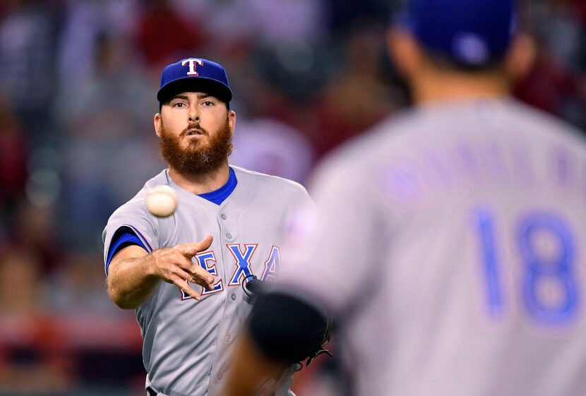 Texas Rangers relief pitcher Sam Dyson, left, tosses a ball hit by Los Angeles Angels'...