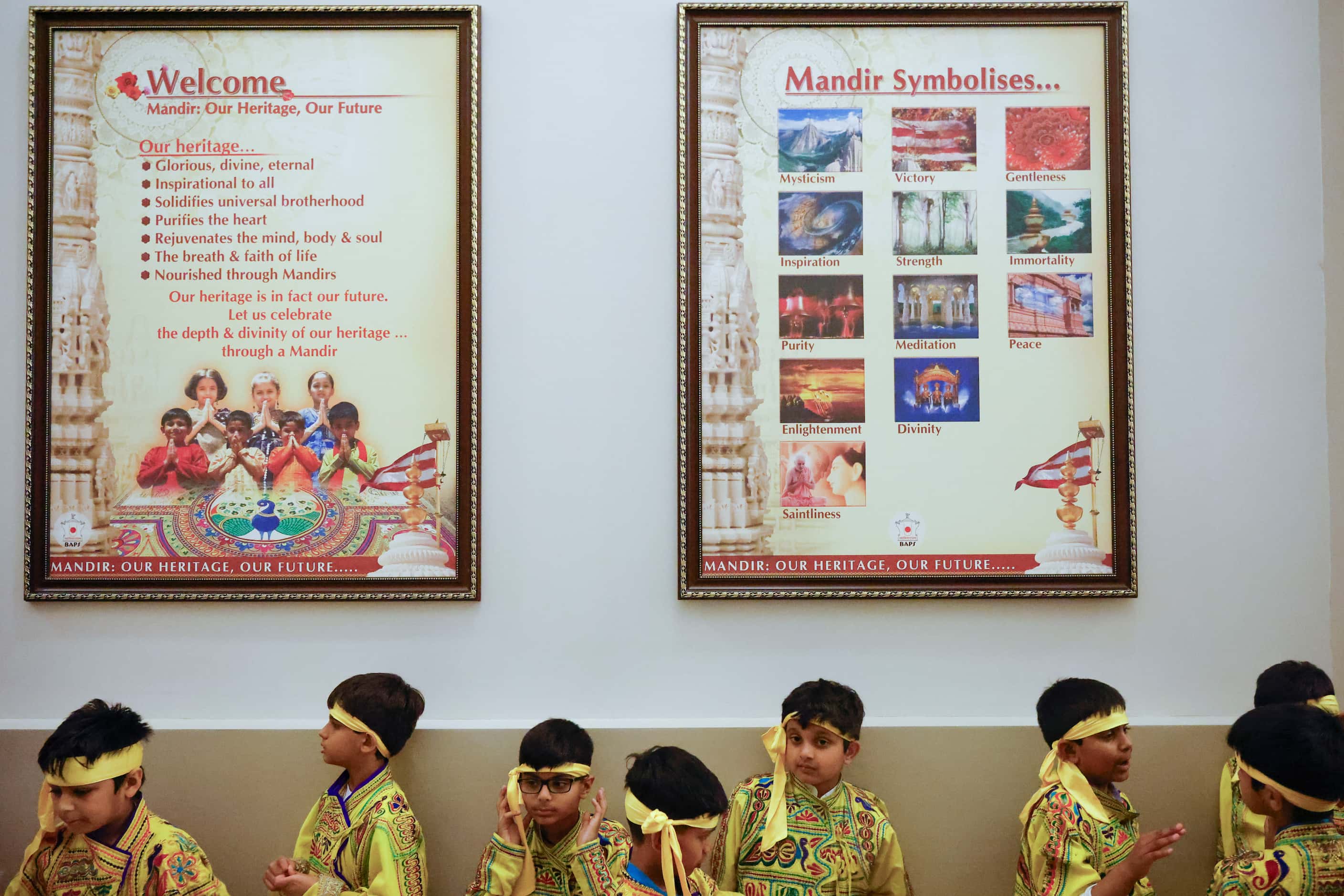 Kids prepare to perform an Indian cultural dance as frames containing the background of BAPS...