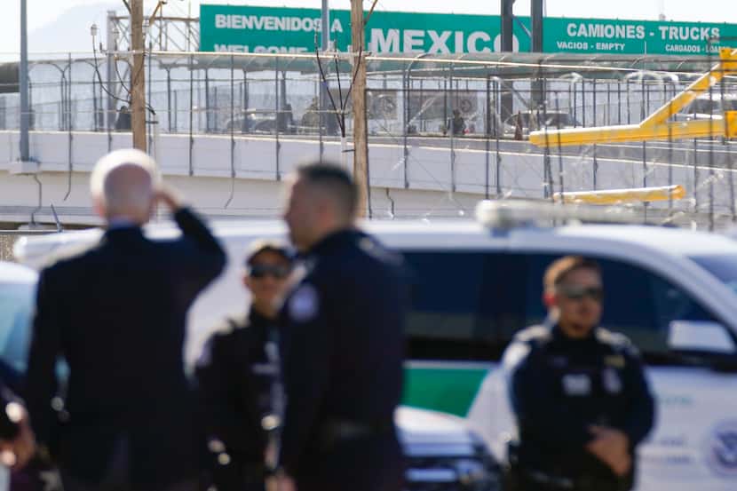 President Joe Biden, left, looks towards a large "Welcome to Mexico" sign that is hung over...