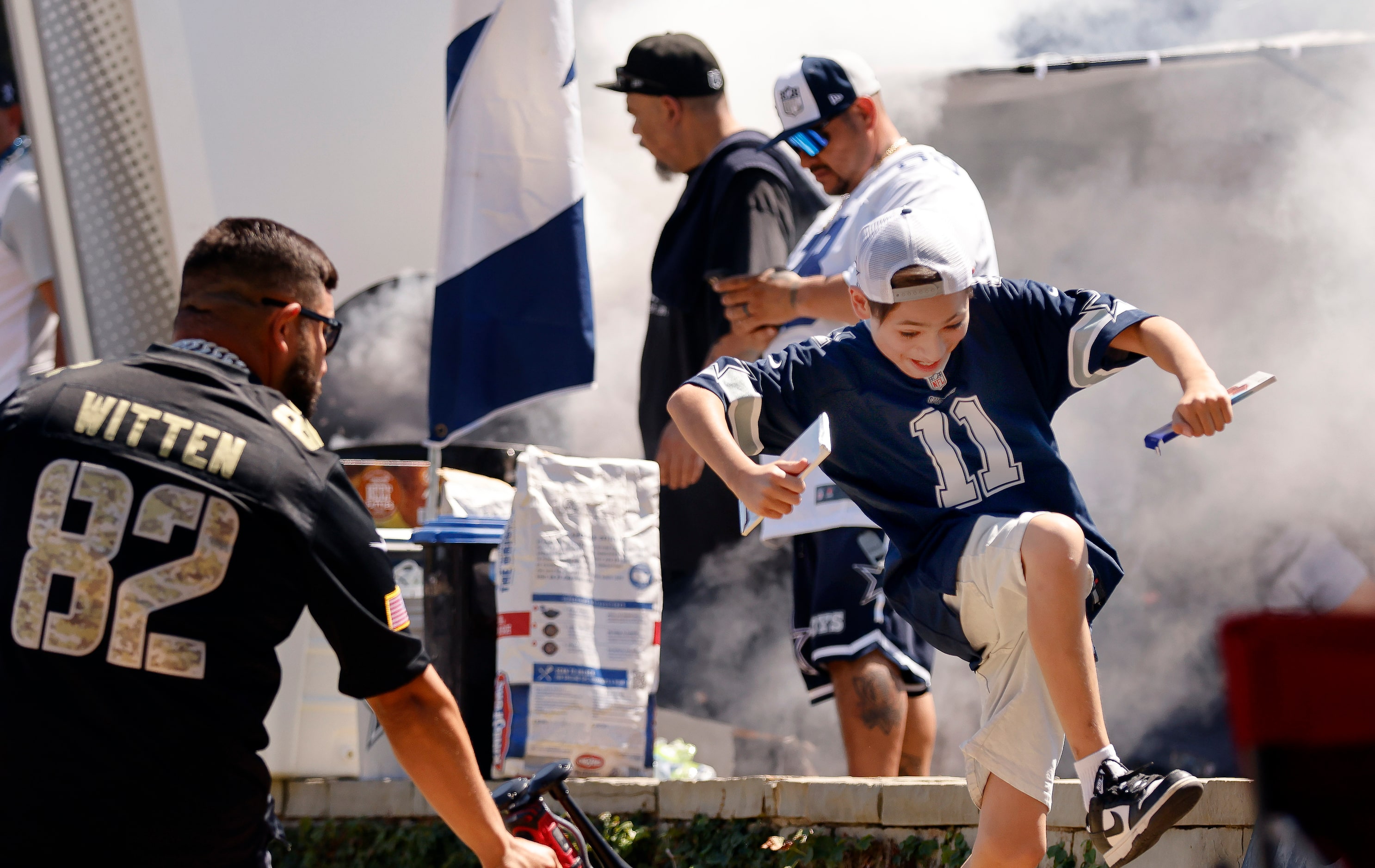 A young Dallas Cowboys fans leaps past another blowing an air horn at a tailgate party...