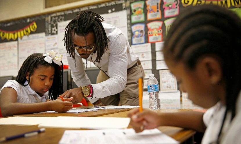 Dallas Cowboys cornerback Brandon Carr helps fourth-graders Arriona Howard (left) and Floyd...