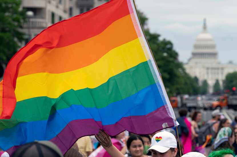 FILE - With the U.S. Capitol in the background, a person waves a rainbow flag as they...