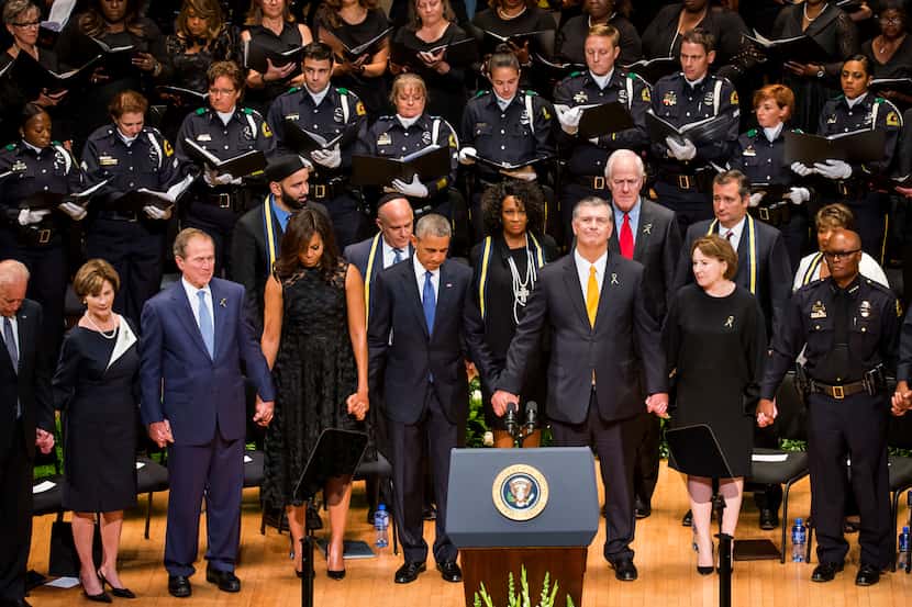 President Barack Obama joins hands with Dallas Mayor Mike Rawlings and other dignitaries...