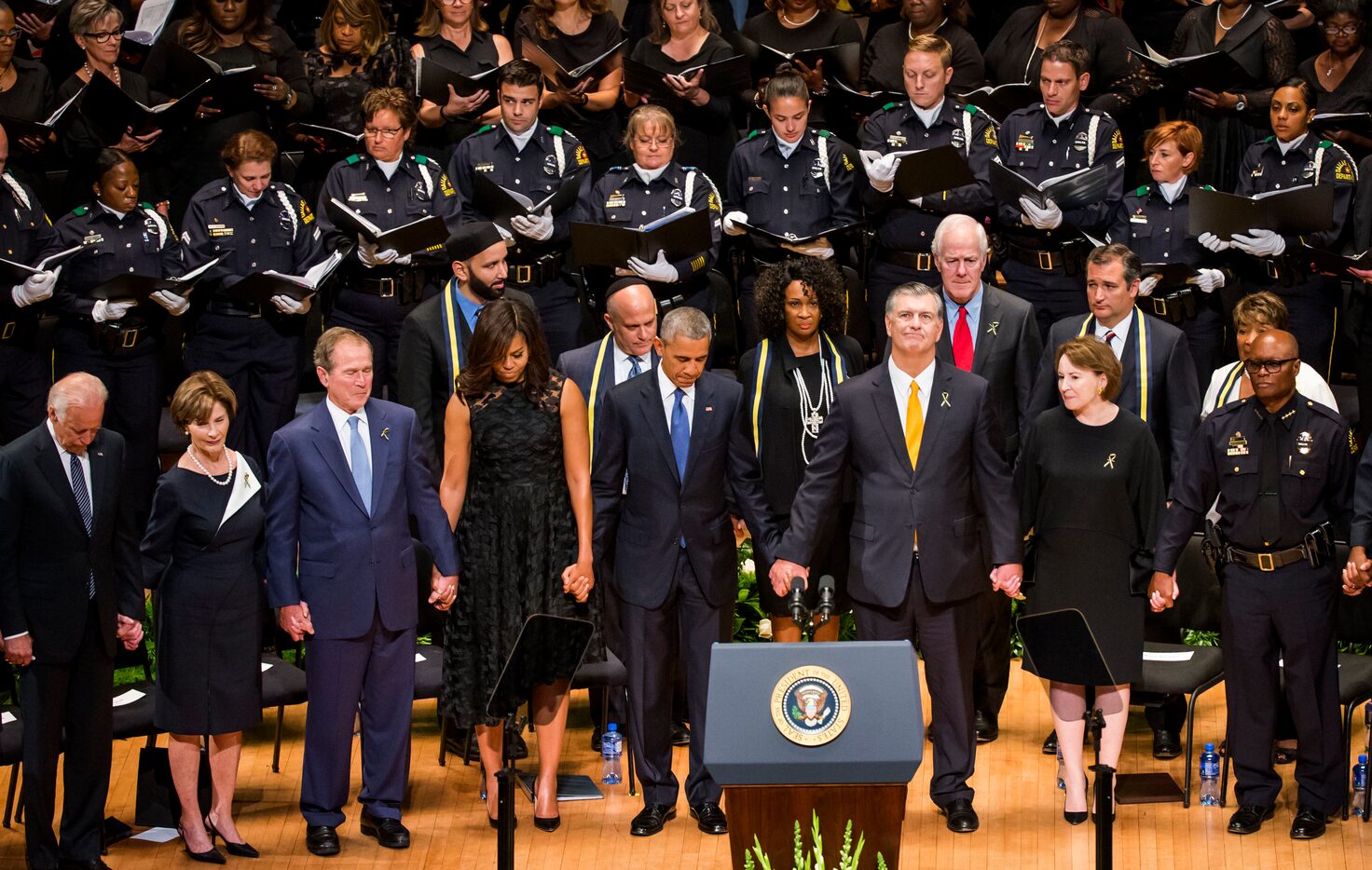 President Barack Obama joins hands with Dallas Mayor Mike Rawlings and other dignitaries...