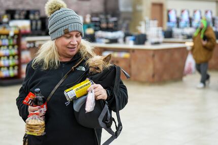 Rena Wilhelm carries her dog Benji as she prepares to check out after picking up snacks at...