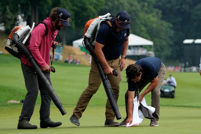 Workers clean up the 18th green after protesters ran onto it during the final round of the...