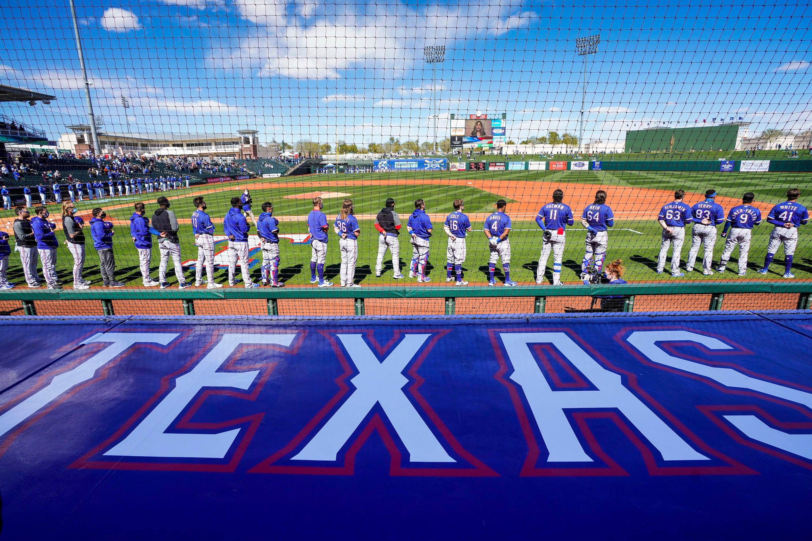 Texas Rangers players stand for the national anthem before a spring training game against...