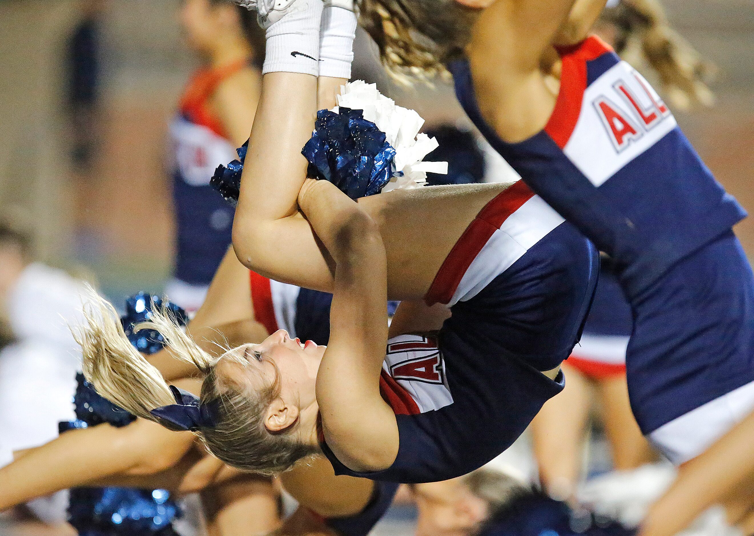 Allen High School cheerleader Riley Pickard, 16, does a back flip after a touchdown during...