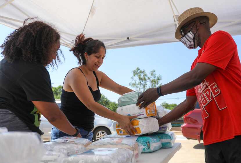 Aide Rojo (center) collected free diapers and wipes from volunteer Ralph Green at an...