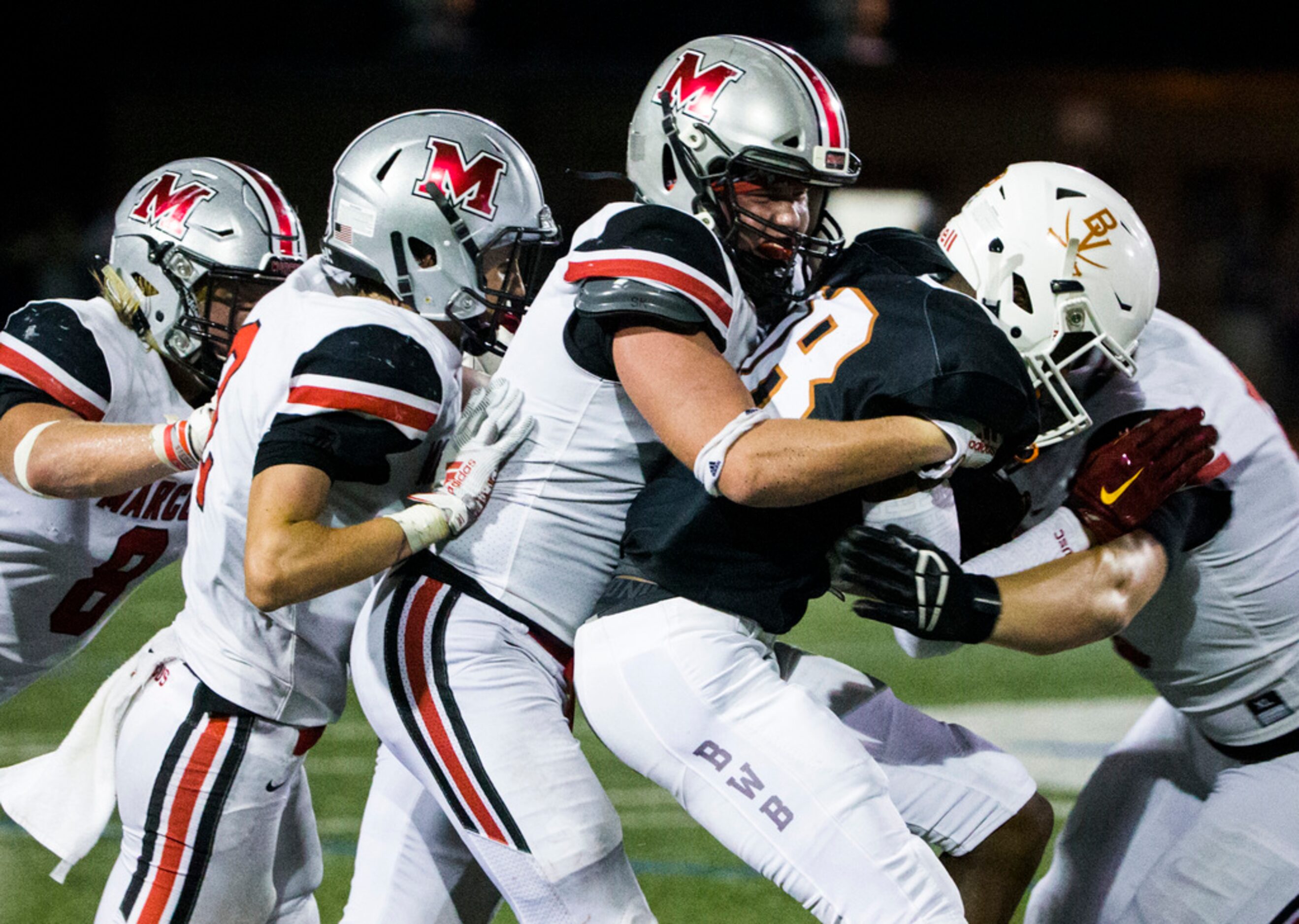 Arlington Bowie wide receiver Jimmy Valsin (18) is tackled by Flower Mound Marcus defenders...