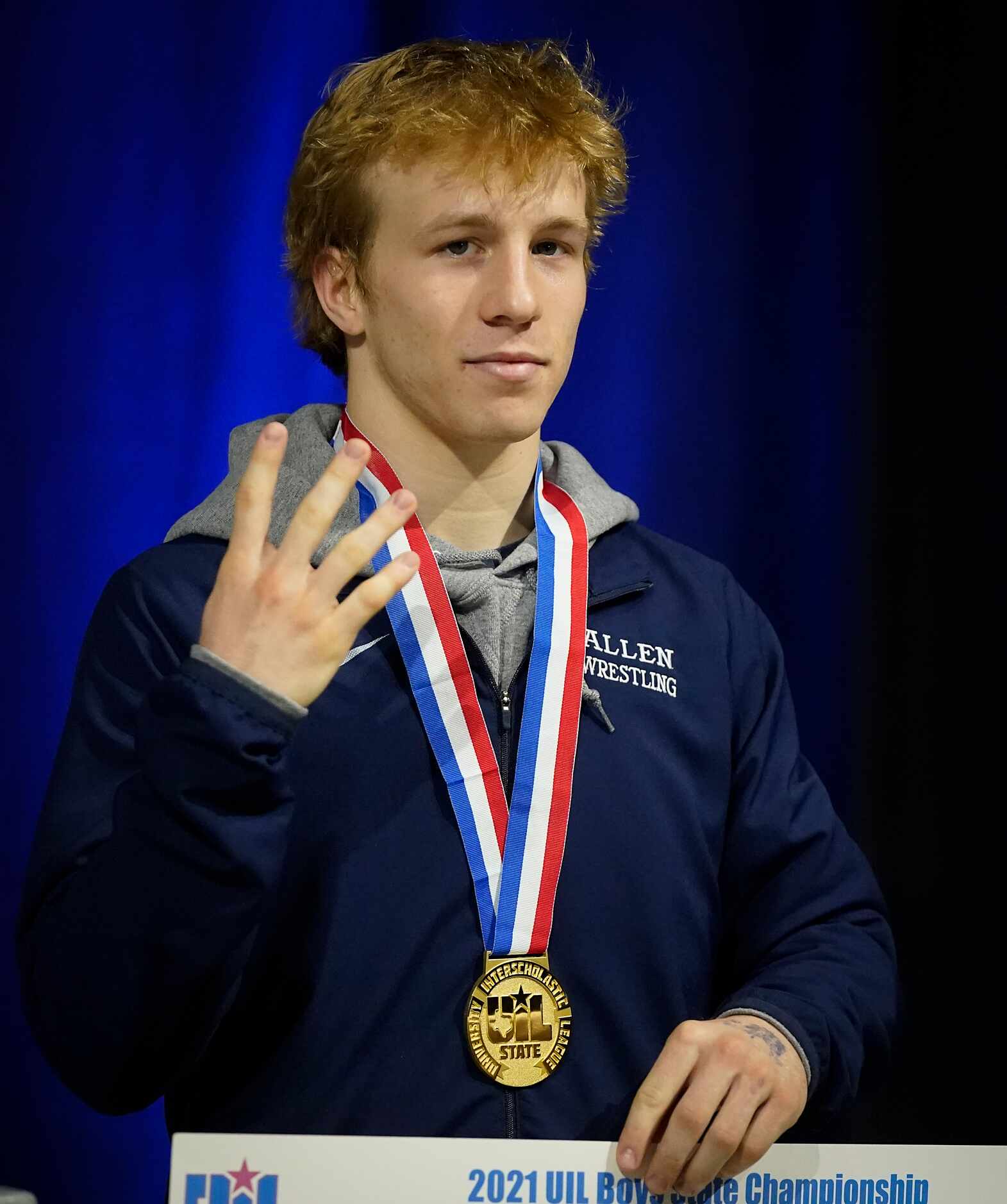Braxton Brown of Allen holds up four fingers on the awards stand after beating  Micah White...