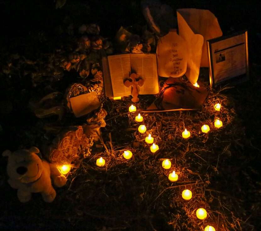 Artificial candles placed in the pattern of a cross light a small tribute set up for Sherin...