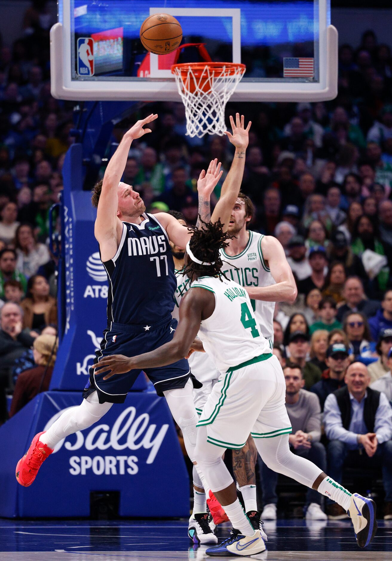 Dallas Mavericks guard Luka Doncic (77) flips a shot over his back alongside Boston Celtics...