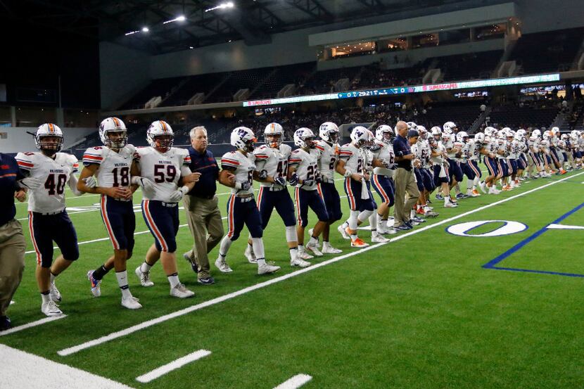 The Wakeland High team walks the field arm in arm before the start of their high school...