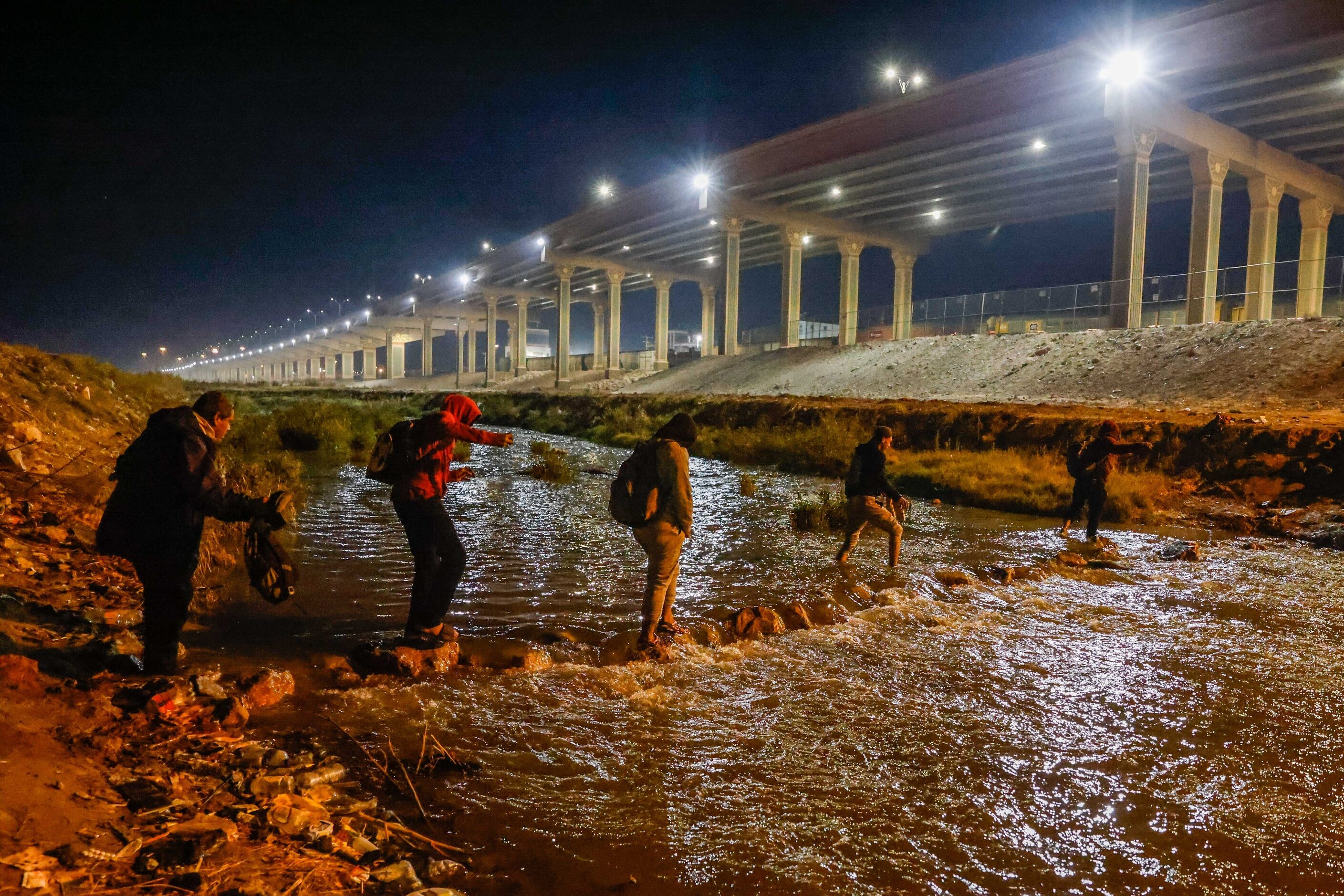 Migrants cross the Rio Grande river and US-Mexico border into El Paso, Texas as seen from...