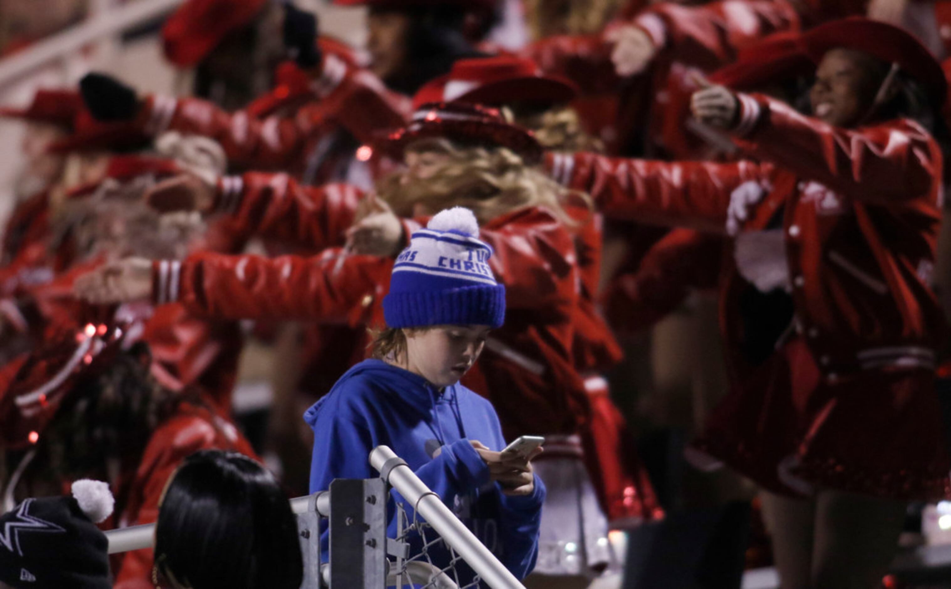 A young Lake Highlands fan uses his cellphone as members of the Lake Highlands drill team...