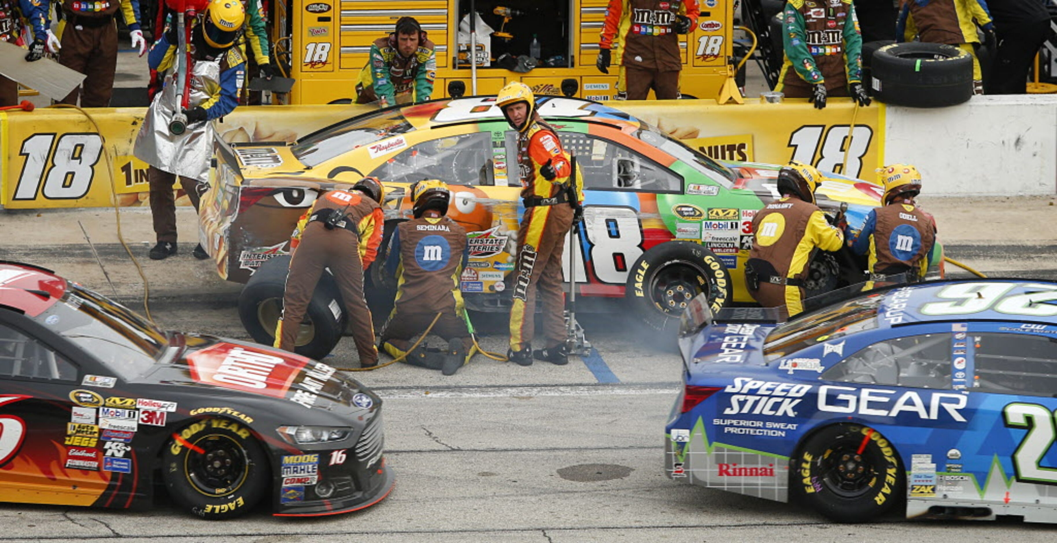 A crewman for Sprint Cup Series driver Kyle Busch (18) points to driver Cole Whitt (26) who...