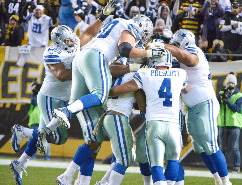Dallas Cowboys quarterback Dak Prescott (4) and the rest of the offense swarm around running...